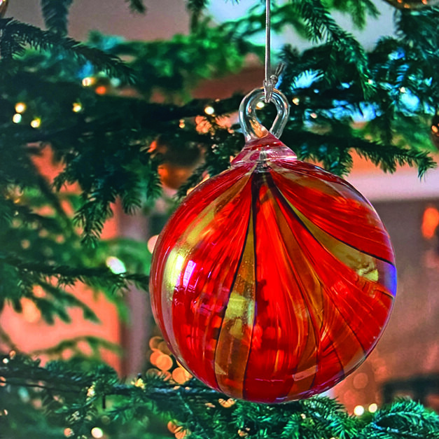 a red and yellow ornament on green tree branches