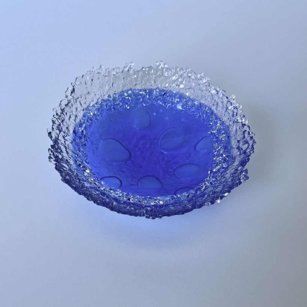 a textured glass bowl with a clear rim and blue center