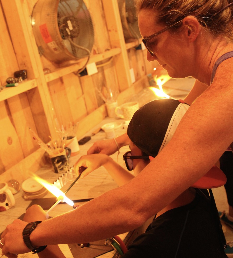 a person teaching a child flameworking