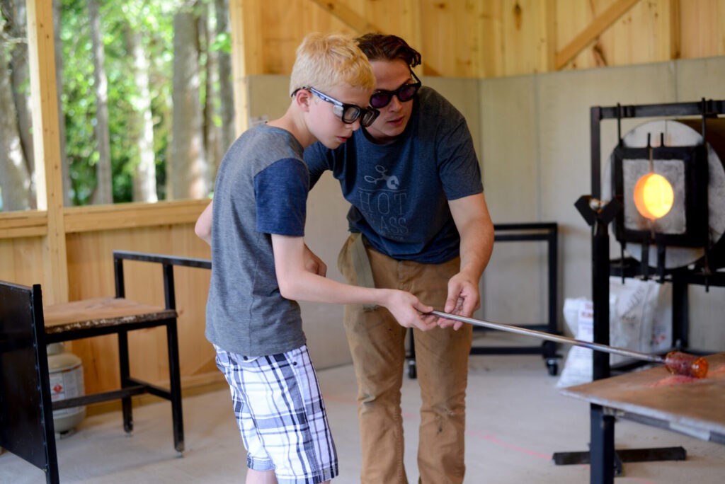 An adult teaching a child glassblowing