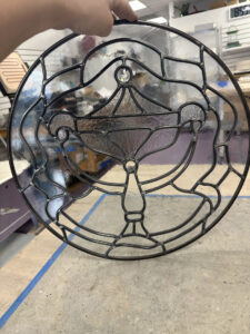 a clear stained glass rondel with a design of a lamp