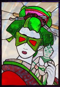 a stained glass window with a geisha in a green mask 