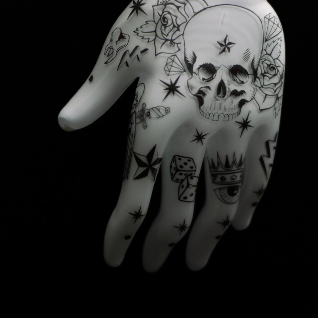 a glass hand sculpture with black graphic details including a skill and dice